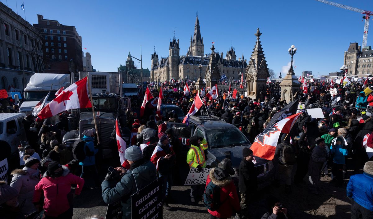 Protestors mingle around vehicles parked on Wellington St. in front of West Block and the Parliament buildings as they participate in a cross-country truck convoy protesting measures taken by authorities to curb the spread of COVID-19 and vaccine mandates in Ottawa on Saturday, Jan. 29, 2022.  (Adrian Wyld)