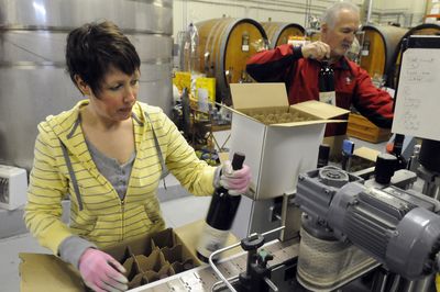 Vicky Jacobsen packs wine coming off the bottling line at Latah Creek Winery on Friday. At right is Latah Creek owner Mike Conway.  (Jesse Tinsley / The Spokesman-Review)