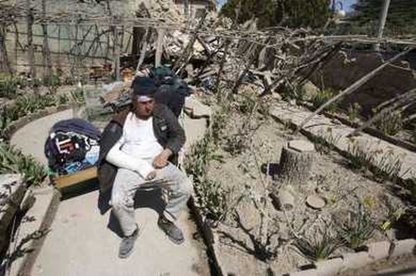 An injured man sits in the garden of his destroyed house after an earthquake in the Italian village of Onna April 6, 2009. A powerful earthquake struck a huge swath of central Italy as residents slept on Monday morning, killing more than 50 people and making up to 50,000 homeless. REUTERS/Chris Helgren (ITALY DISASTER) REUTERS/Chris Helgren (The Spokesman-Review)
