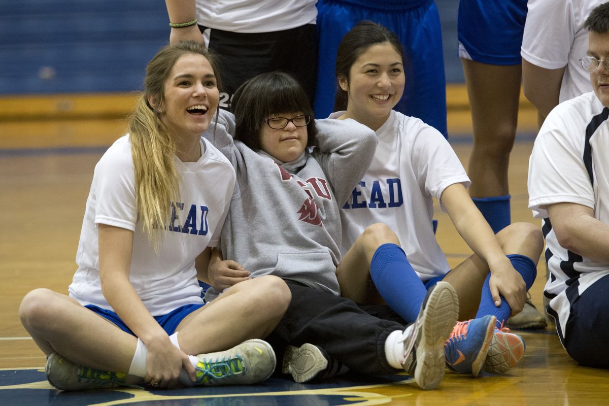 Unified Sports partners, Anna Kessler, left, and Madeline Leslie, right, gather with Special Olympics athlete Sophya Bovdyr as members of the Mead High School Unified Sports soccer team gather for a group picture in the school’s gym, April 24. (Dan Pelle)