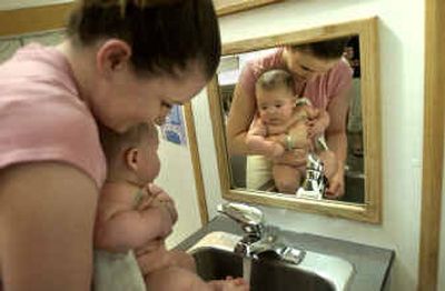 
Alexander Smith watches as his mom, Theresa Smith, washes the paint from his feet after the parent and child activity. 
 (Holly Pickett / The Spokesman-Review)