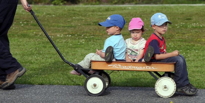 Anne Kosel,1, center, sits between her  brothers Alan,3,left, and Tim,5, as they are pulled by their father, Zach, in East Bremerton, Wash.  on May 22, 2010. (Larry Steagall / Kitsap Sun)