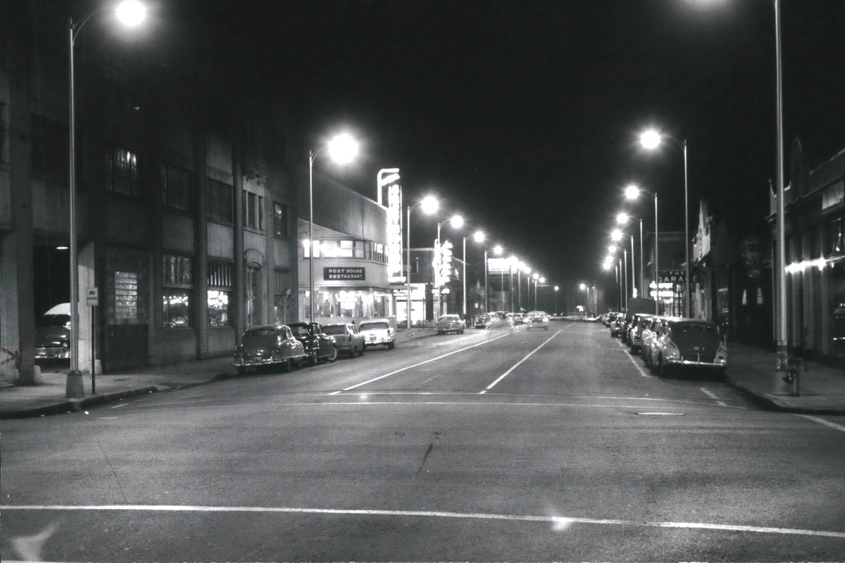 1958: Beyond the three-story auto garage at far left, Spokane’s Union Bus Depot glows with light from a “Greyhound” sign at 1125 W. Sprague Ave. A sign also advertises the Post House restaurant, a combination cafeteria and sit-down restaurant that became a fixture in hundreds of Greyhound stations across the nation.  (Photo Archive/The Spokesman-Review)