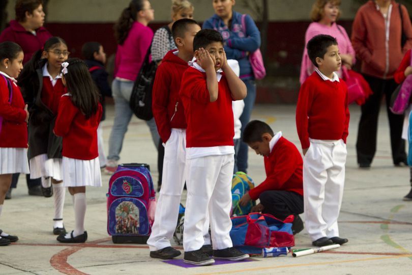 Students stand in a school courtyard as they wait for the first day of classes to begin, in Mexico City, Monday, Aug. 19, 2013. Mexican children returned to classrooms Monday, and they were getting a quick lesson: Not just school kids make mistakes. Their brand new textbooks have the kinds of errors that they are supposed to be learning not to make: words written with a 