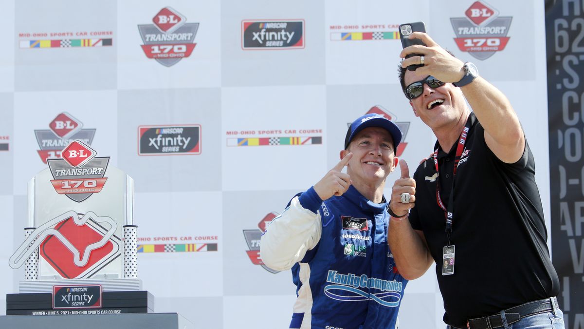 A.J. Allmendinger, left, takes a photo with car owner Matt Kaulig as they celebrate in Victory Lane after winning the B&L Transport 170 NASCAR Xfinity Series auto race at Mid-Ohio Sports Car Course on Saturday, June 5, 2021, in Lexington, Ohio.  (Tom E. Puskar)