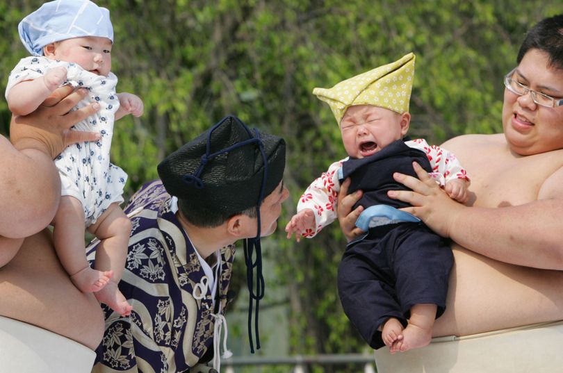 A couple of toddlers, Rintaro Doi, left, and Hiyori Tsuchiya, right, held by college sumo wrestlers, compete in the baby screaming contest, known as Naki Sumo (Crying Sumo), a traditional ritual performed as a prayer for the good health of children, at Senso-ji temple in Tokyo, Saturday, April 28, 2007. (Koji Sasahara / Associated Press)