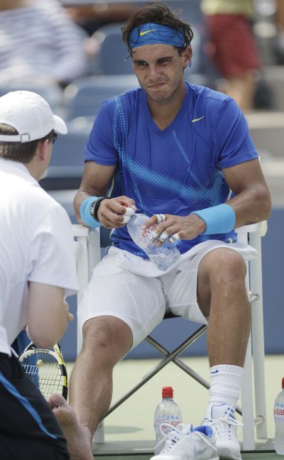 A trainer works on Rafael Nadal’s foot during his match against David Nalbandian. (Associated Press)