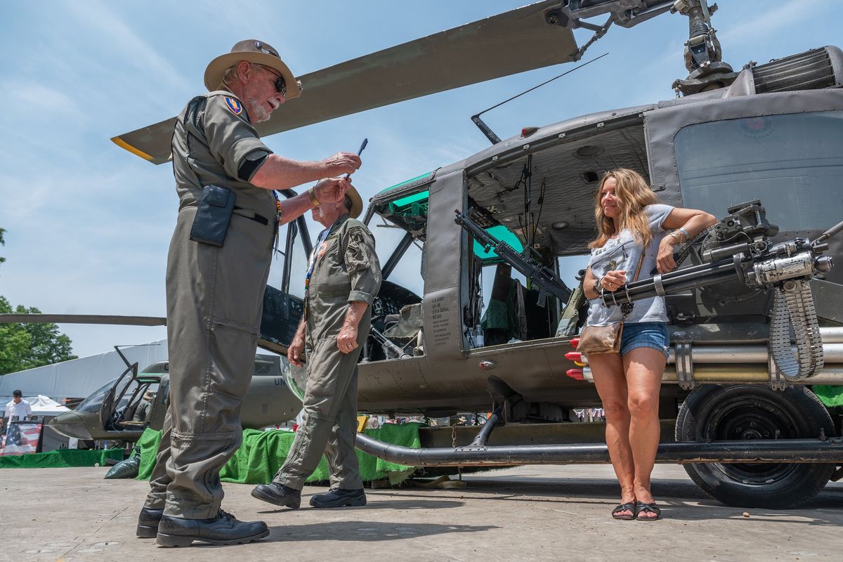 Kristina Micali, whose father served in the Navy during the Vietnam War, has her photo taken by retired Army pilot Victor Rose Jr. in front of a helicopter Thursday on the National Mall.  (Craig Hudson/For the Washington Post)