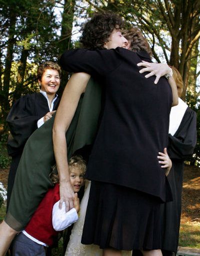 
Mary Norton leans over her adopted son, Mickey Baker-Norton, 6, and hugs her partner, Wendy Baker, as Judge Donna Nesselbush, left, looks on during a wedding ceremony Sunday in Attleboro, Mass. The couple, who live in Providence, R.I., won Massachusetts Supreme Court decision to allow same-sex couples from Rhode Island to marry.
 (Associated Press / The Spokesman-Review)