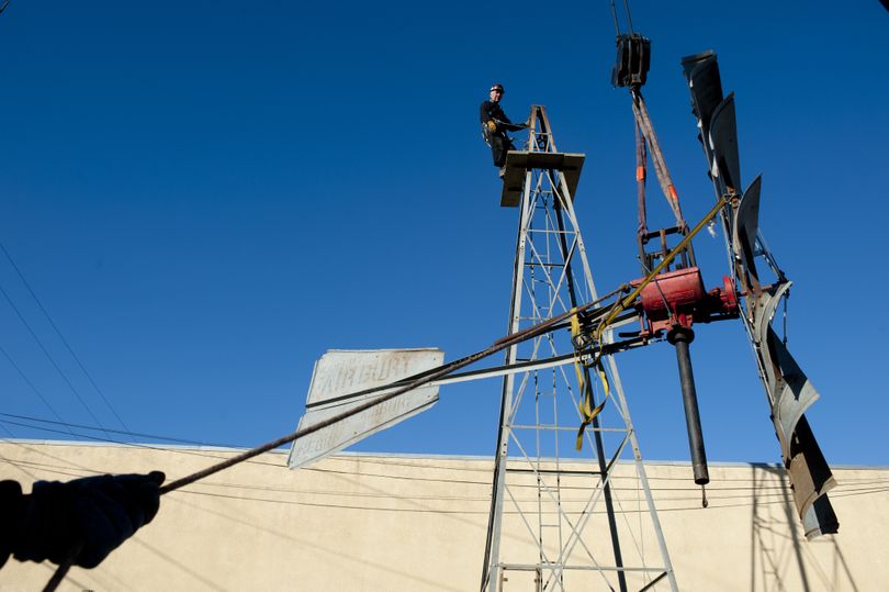 Hugh Grim watches from the top of a Fairbury farm windmill tower as his son, Jim, keeps a hand on a guide-line as they use a crane to lift the windmill to the top of its tower Tuesday at the Spokane Valley Heritage Museum. (Tyler Tjomsland)