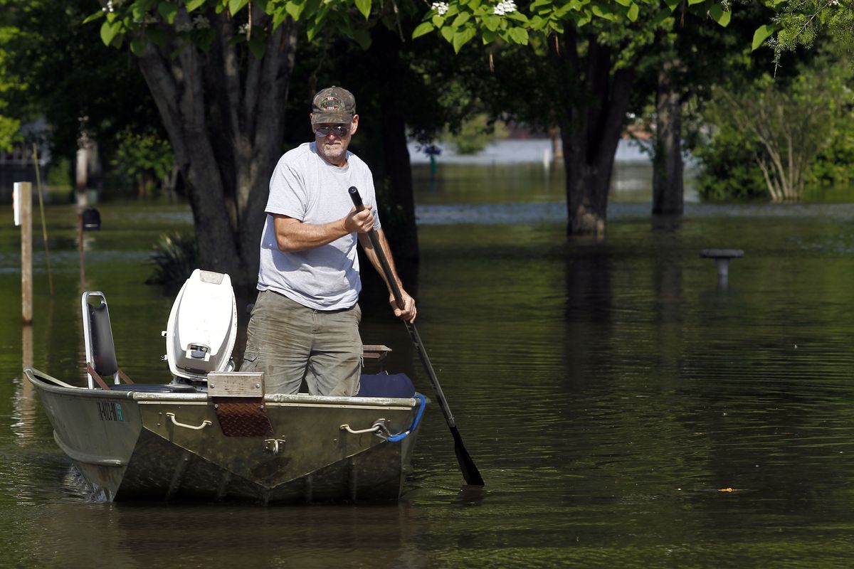 Above: Joe Bledsoe paddles a boat through his neighborhood Saturday in Bogota, Tenn. (Associated Press)