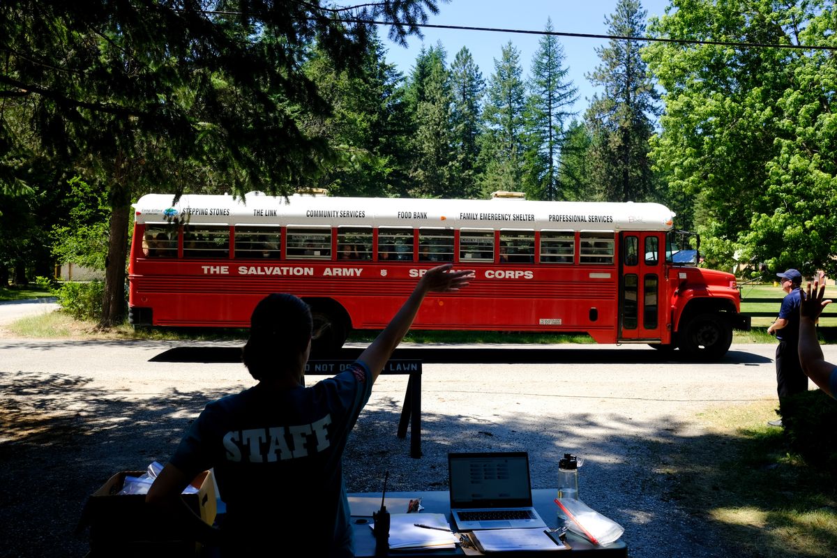 A staff member waves as new campers arrive via bus on Monday, June 28, 2021, at Camp Gifford, The Salvation Army
