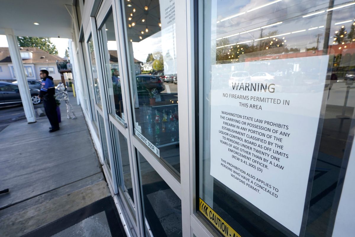 A sign warns that firearms are prohibited at Mary Mart as armed security guard Austin MacMath stands watch outside at left.  (Ted S. Warren)