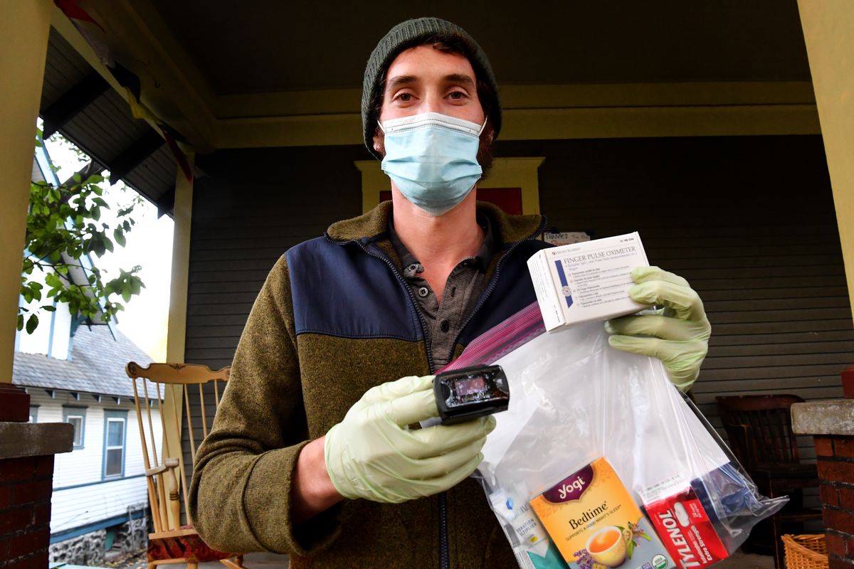 Jeremy Taylor, a volunteer with the Community Health Monitoring Program, holds a pulse oximeter and a care package of supplies the organization delivers to people who test positive for COVID-19.  (Tyler Tjomsland/THE SPOKESMAN-REVIEW)