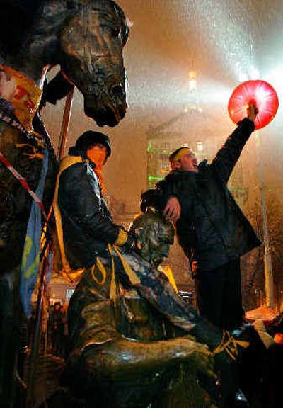 
Ukrainian supporters of opposition candidate Viktor Yushchenko climb on top of a statue in Kiev's main square to protest alleged election fraud. 
 (Associated Press / The Spokesman-Review)