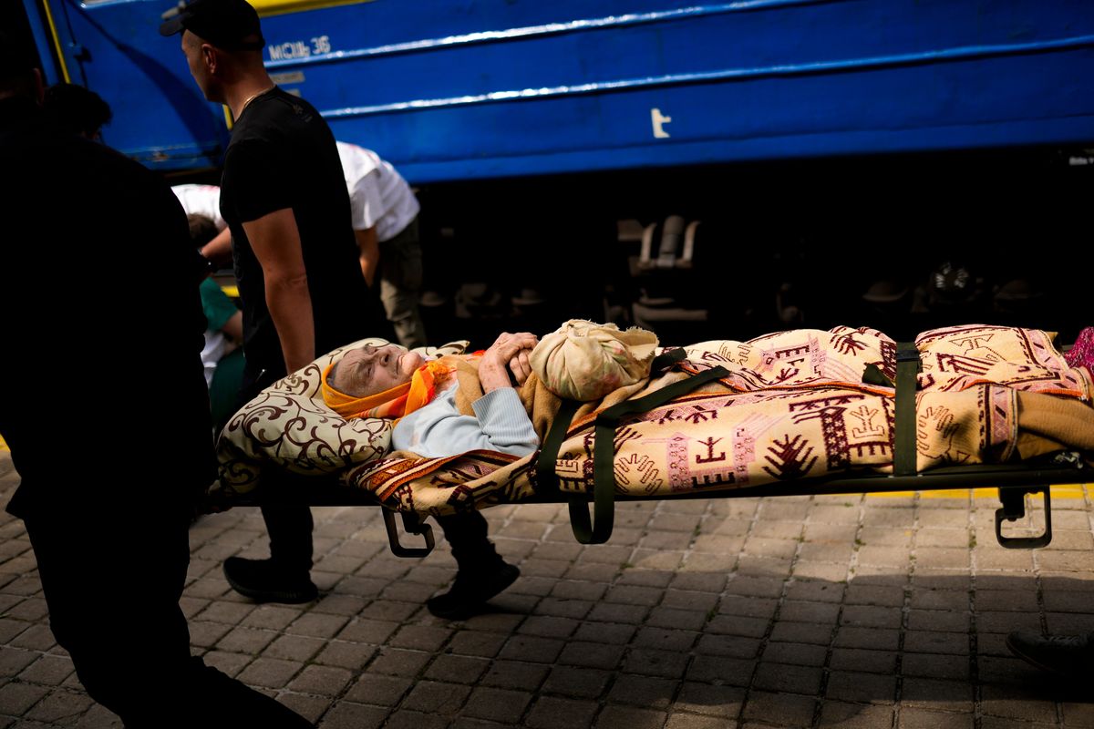 An elderly patient is carried on a stretcher to board a medical evacuation train run by MSF (Doctors Without Borders) at the train station in Pokrovsk, eastern Ukraine, Sunday, May 29, 2022. The train is specially equipped and staffed with medical personnel, and ferries patients from overwhelmed hospitals near the front line, to medical facilities in western Ukraine, far from the fighting.  (Francisco Seco)