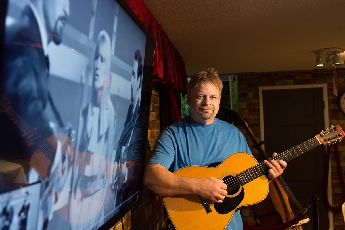 Spokane musician Kelly Bogan poses for a photo next a screen playing a Peter Paul and Mary video on Friday, June 9, 2017, at the Amend Music Center in Spokane, Wash. Bogan spent a year transcribing the bulk of the Peter Paul and Mary albums. Note for note, including harmonies and guitar parts. (Tyler Tjomsland / The Spokesman-Review)