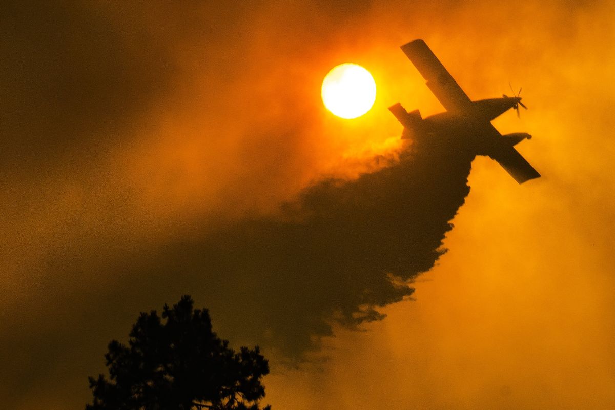 A firefighting aircraft drops water Friday on a wildfire along the Rimrock Drive bluff west of downtown Spokane.  (Colin Mulvany/The Spokesman-Review)