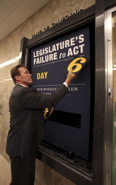 After the Legislature’s approval of a state budget, Gov. Arnold Schwarzenegger removes the numbers from the “deficit clock” he employed to keep track of the duration of a special session called to address Calfornia’s fiscal problems.  (Associated Press / The Spokesman-Review)