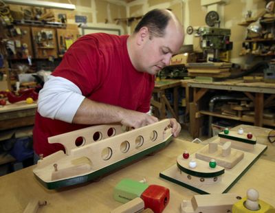 Toymaker Jason Rounds assembles a wooden toy ferry boat in his Marysville, Wash., shop. Rounds’ creations are handmade from hardwood. (Associated Press)