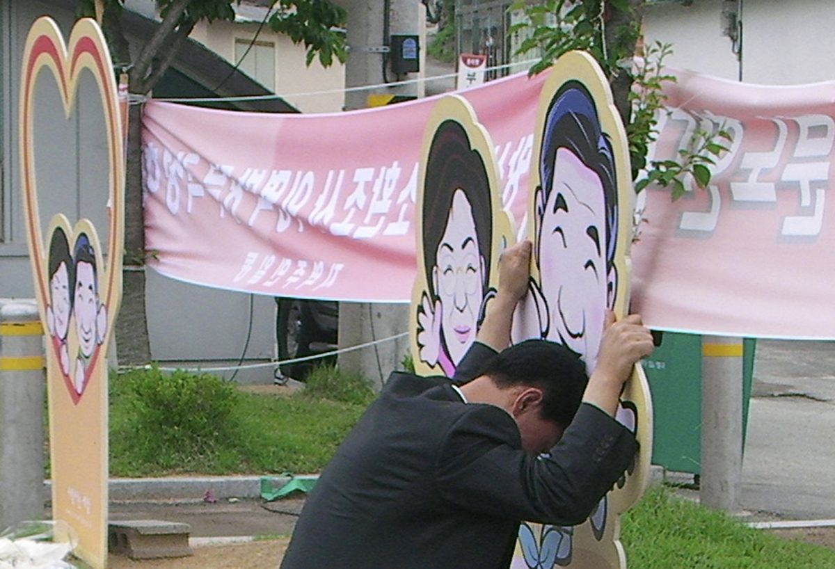 A supporter of former President Roh Moo-hyun holding a cartoon cutout of Roh, right, and his wife, Kwon Yang-sook, weeps near the Rohs’ home in Gimhae, South Korea, today. (Associated Press / The Spokesman-Review)