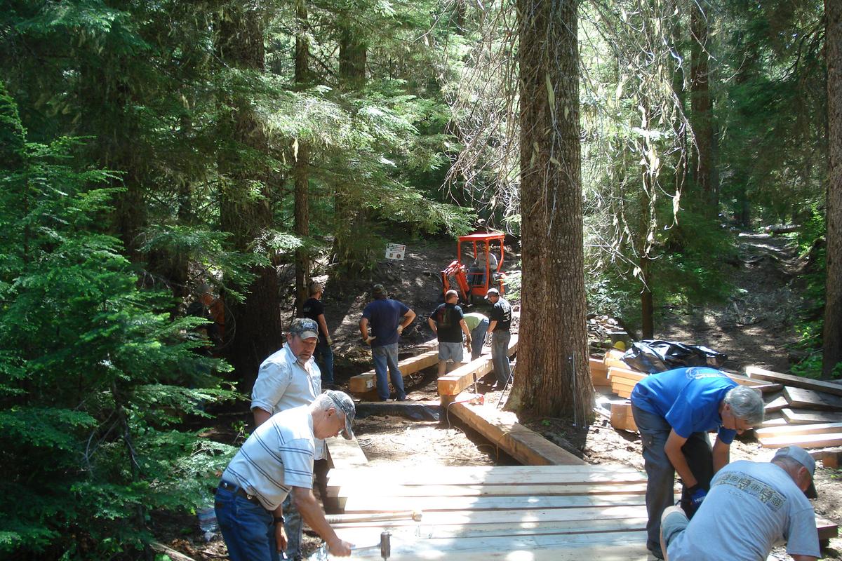 Volunteers from area four-wheel-drive and motorcycle clubs help replace the 120-foot puncheon on the Naches Trail.