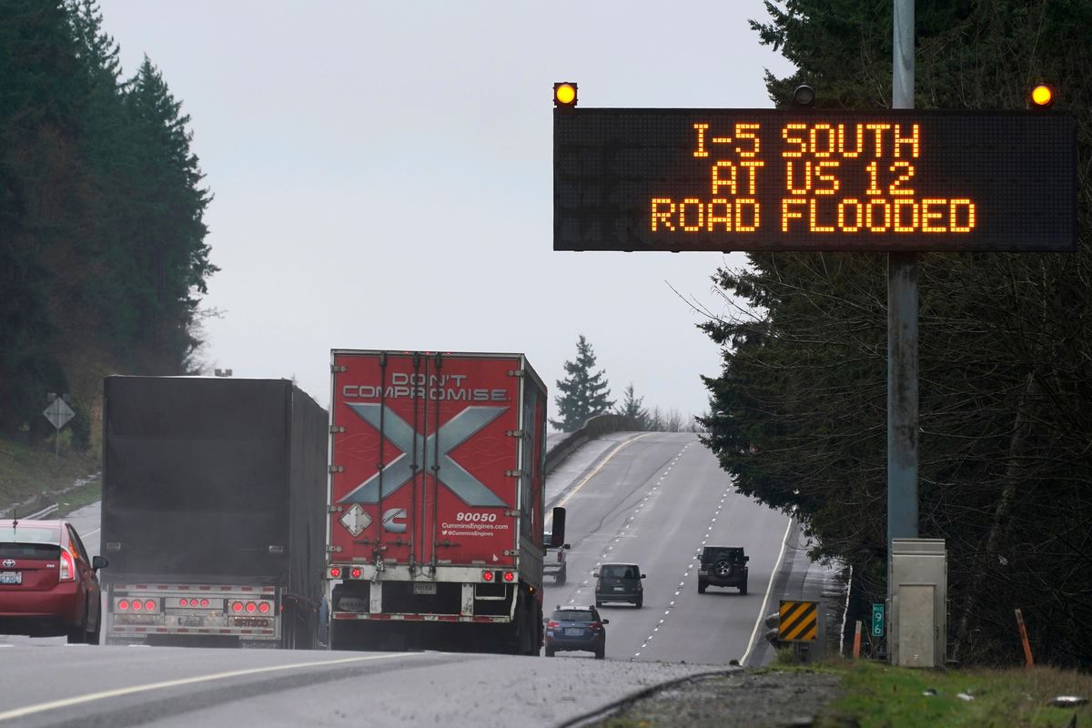 A sign warns drivers of a section of Interstate 5 that is closed ahead due to rising flood water from the Chehalis River, Friday, Jan. 7, 2022, near Rochester, Wash. Rain and snow continued to fall across the Pacific Northwest Friday, causing flooding and concerns about avalanche danger in the mountains.  (Ted S. Warren)