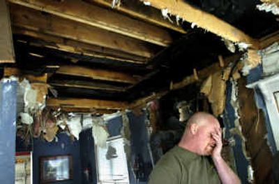 
Thad Blauert covers his face Tuesday morning in his living room. Firefighters had to tear apart walls and ceilings in his home at 11904 E. Valleyway to put out a fire Monday evening. Blauert and his wife, Sonja, were asleep upstairs when the fire started, but were able to get out safely. 
 (Holly Pickett / The Spokesman-Review)
