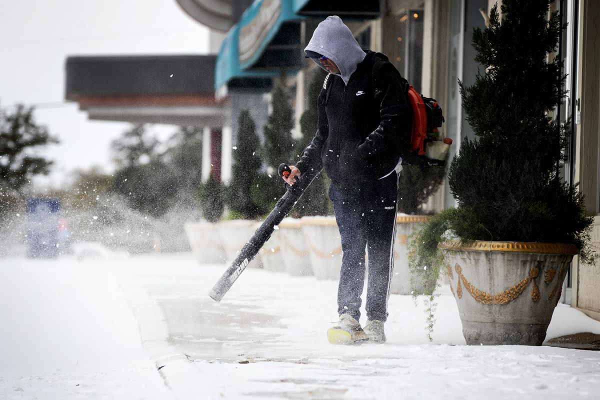 Scott Blocker uses a blower to clear the sidewalks of snow in front of a shopping center on Camp Bowie Blvd. Wednesday, Feb. 17, 2021, in Fort Worth, Texas.  (Yffy Yossifor)