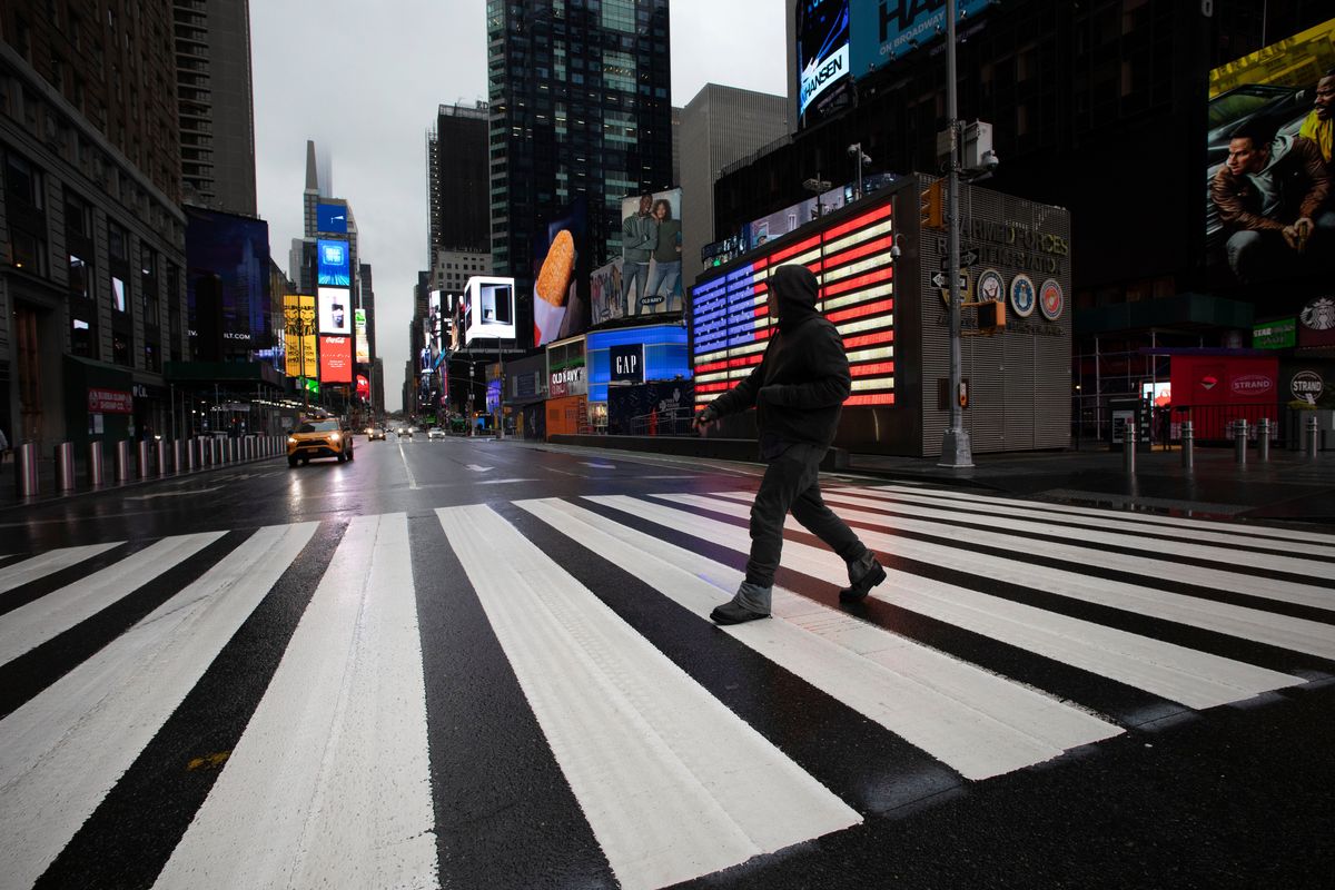 FILE – A man crosses the street in a nearly empty Times Square, which is usually very crowded on a weekday morning in New York on March 23, 2020.  (Mark Lennihan)