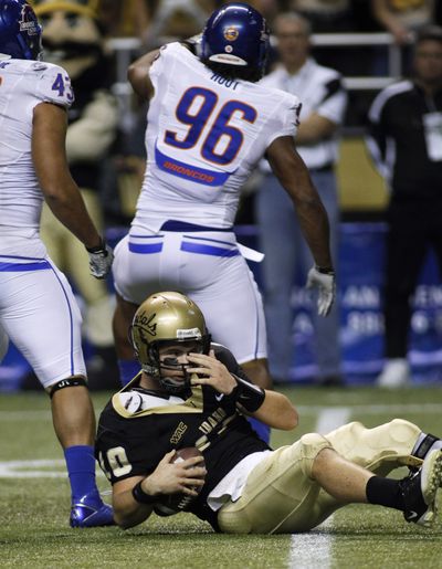 Idaho quarterback Nathan Enderle sits on the turf after being sacked by Boise State's Jarrell Root (96). (Ted Warren / Associated Press)
