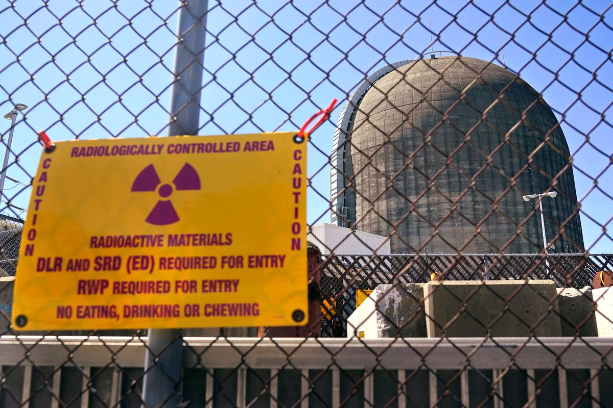 FILE— A sign warning of radioactive materials is seen on a fence around a nuclear reactor containment building on Monday, April 26, 2021, a few days before it stopped generating electricity at Indian Point Energy Center in Buchanan, N.Y. The Biden administration is launching a $6 billion effort to save nuclear power plants at risk of closing, citing the need to continue nuclear energy as a carbon-free source of power that helps to combat climate change.  (Seth Wenig)
