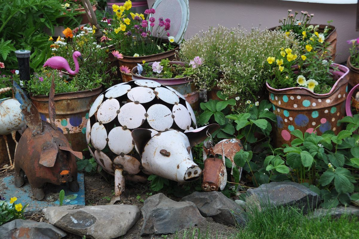 Robin Ann Bienemann’s backyard is anything but tame. Here a salvaged art piece of a white pig shares space with just a few of the other repurposed and found pieces of art that share space with bright annuals and perennial plantings.  (Pat Munts/For The Spokesman-Review)