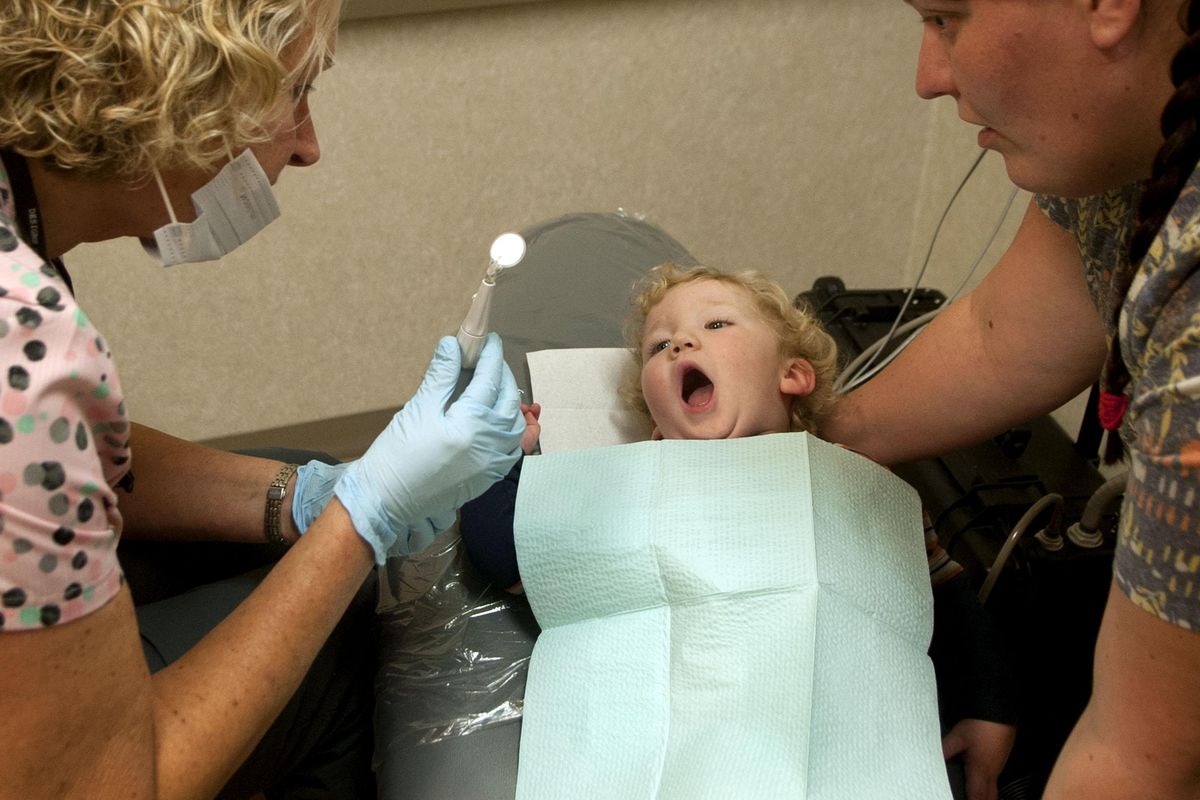 Jacob Edwards, 2, of Pinehurst, opens wide for Carrie Busch RDH-EA, left and his mother Nichole during Dental Days at Panhandle Health in Hayden on Wednesday, Nov. 20, 2019. Dental Days are free appointments for low-income families and kids in north Idaho. (Kathy Plonka / The Spokesman-Review)