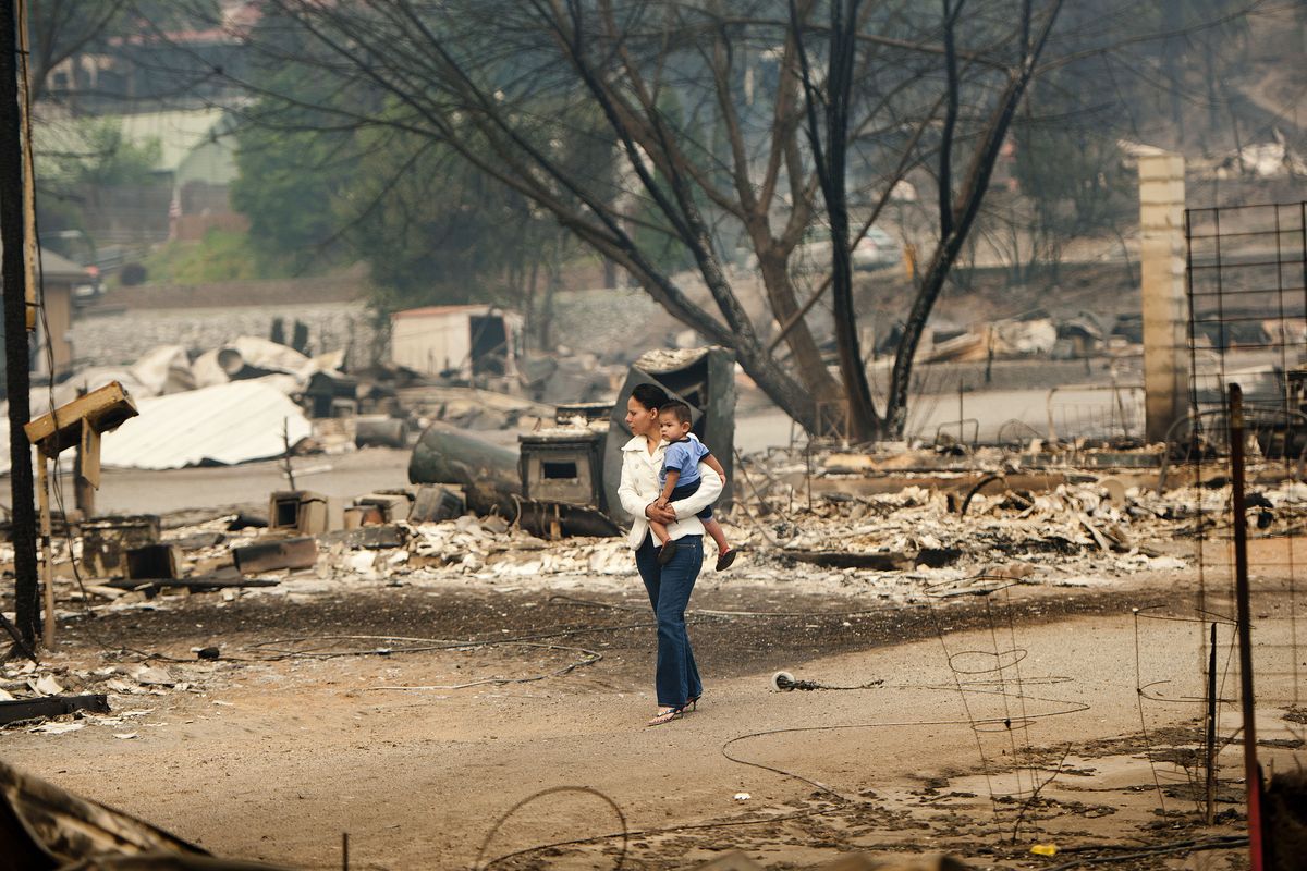 Emma Franco carries Jovonnie Lobato through the lot where her home once stood on Friday in Pateros, Wash. “I have nothing left,” she said. “No papers, no clothes.” (Tyler Tjomsland)