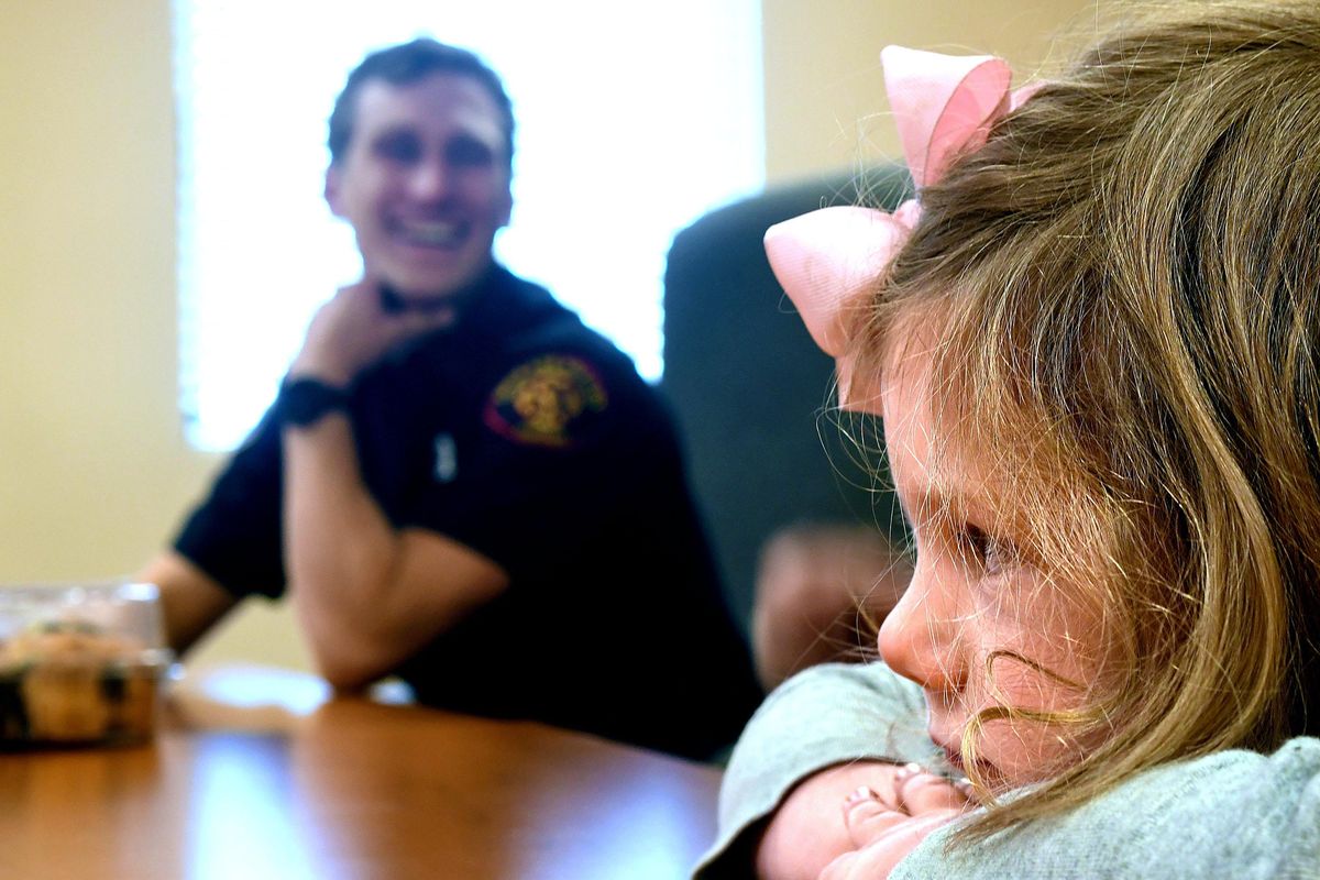 Olivia Canner, 5, listens to her mother tell the story of how she got her foot stuck in the frame of her bicycle, during an interview at Spokane Valley Fire Station 8 on Saturday, June 23, 2018. The fire department was dispatched and had to cut the frame to free her. The firefighters then used money from the Spokane Valley Firefighters Benevolent Association to buy a new bike for her. (Kathy Plonka / The Spokesman-Review)