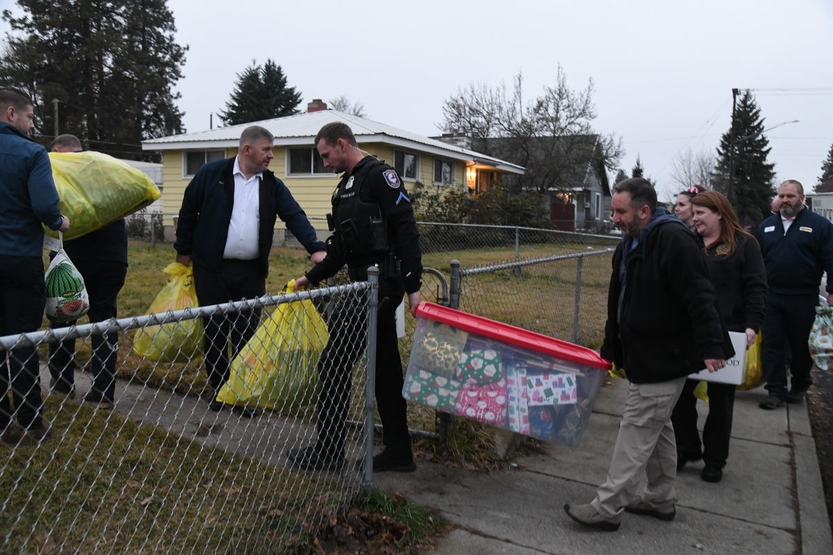 Members of Spokane Police Department and Les Schwab Tire Center unload a trailer full of Christmas presents for a family in need at a home in north Spokane Thursday afternoon.  (James Hanlon/The Spokesman-Review)