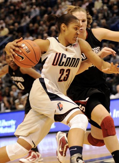 Connecticut’s Maya Moore drives past Stanford’s Kayla Pedersen during first half of Wednesday’s game.   (Associated Press)