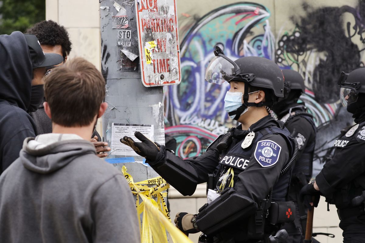A police officer engages with a protester Wednesday in Seattle, where streets had been blocked off in an area demonstrators had occupied for weeks.  (Associated Press)
