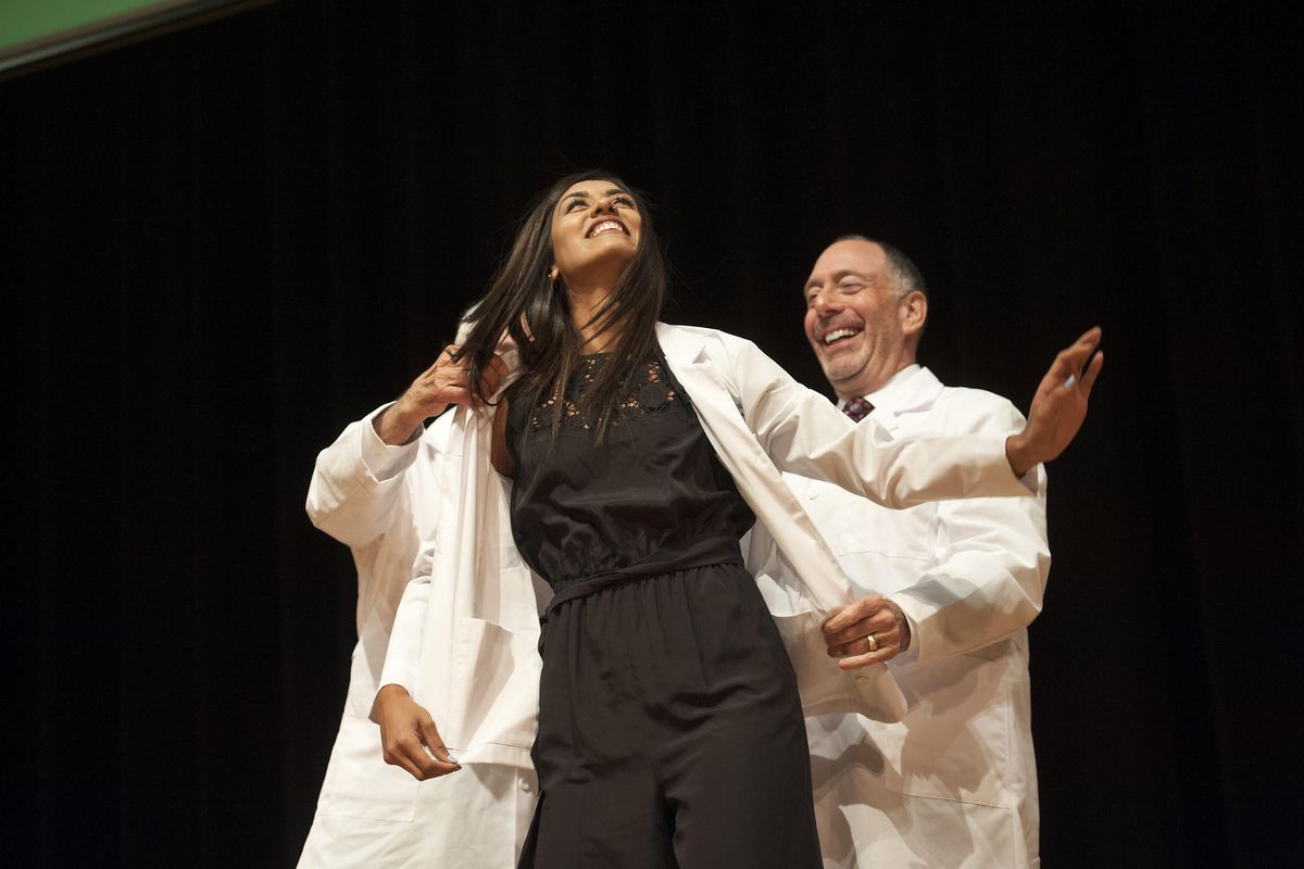 Ekra Rai smiles as she accepts the white coat from Dr. Larry Schecter, left, and Dr. Steven Grossman, right, during the Inaugural White Coat Ceremony of Washington State University