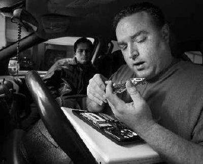 
Demetrios Leontari repairs an iPod from the driver's seat of his minivan in New York. A self-styled iPod doctor, the affable Leontaris is a full-time iPod resuscitator, part of a cottage industry catering to music devotees whose musical companions have malfunctioned, usually from mistreatment. 
 (Associated Press / The Spokesman-Review)