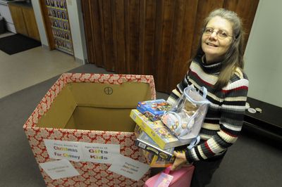 Sally Shamp, of the Cheney United Church of Christ, stands Wednesday with  toys and a box that will be part of  a Christmas campaign in Cheney.  (Jesse Tinsley / The Spokesman-Review)