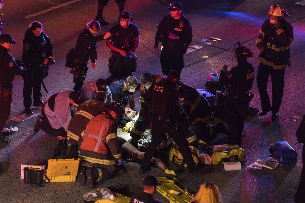 Emergency workers tend to an injured person on the ground after a driver sped through a protest-related closure on the Interstate 5 freeway in Seattle, authorities said early Saturday, July 4, 2020. Dawit Kelete, 27, has been arrested and booked on two counts of vehicular assault. (James Anderson)