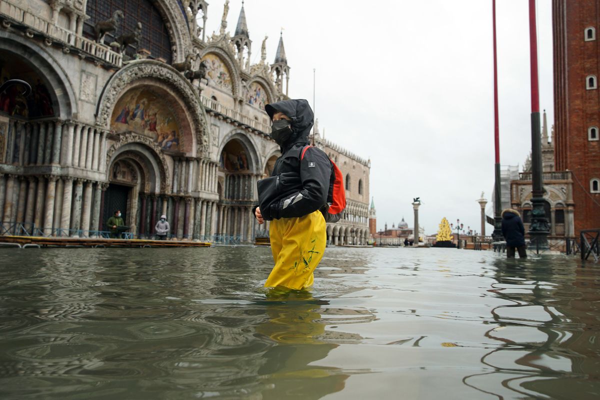 People wade their way through water on Dec. 8 in flooded St. Mark’s Square following a high tide in Venice, Italy. The city now gets floods in August.  (Anteo Marinoni)