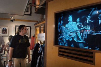 Elvis Presley is shown on video playing on a television during one of his early performances while Skip de Lyon, left, of Cary, N.C., looks around a gift shop across the street from Graceland in Memphis, Tenn.
 (The Spokesman-Review)