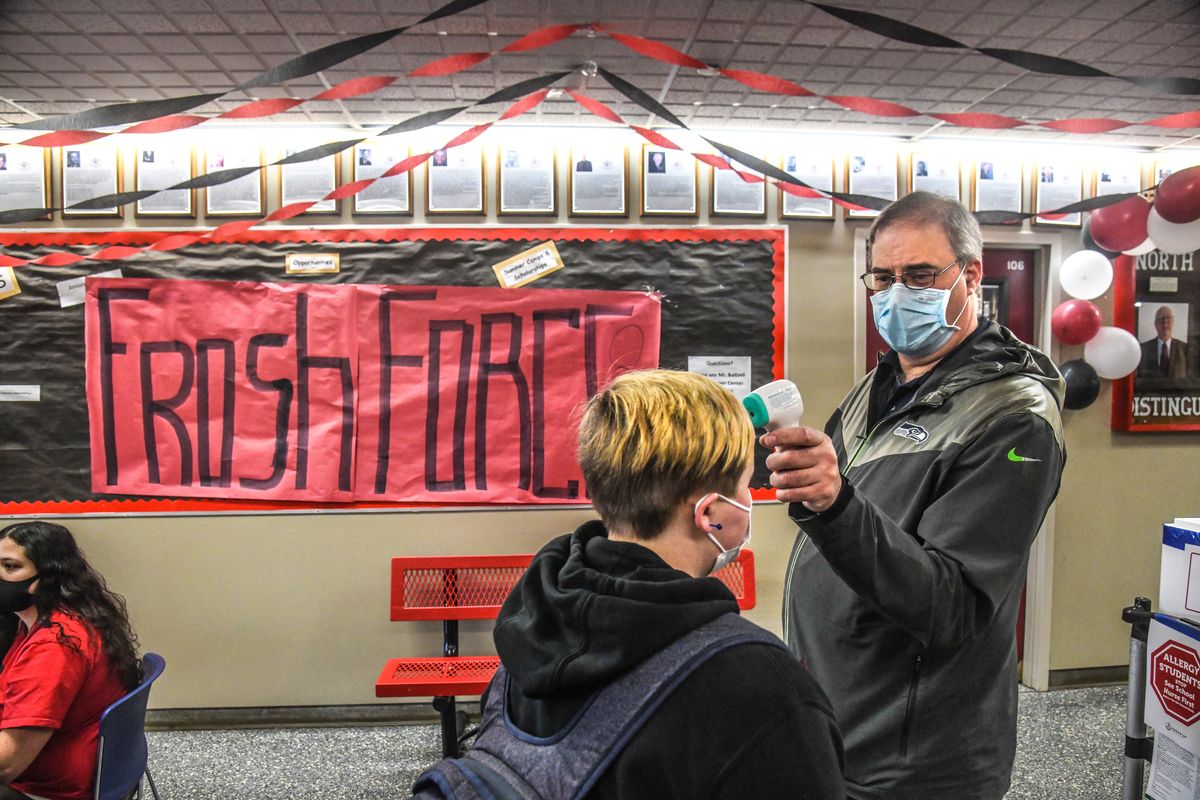 Peter Cogswell temperature checks freshman entering North Central High School for the first day of in-person classes this school year, Monday morning, March. 1, 2021 in Spokane.  (DAN PELLE/THE SPOKESMAN-REVIEW)