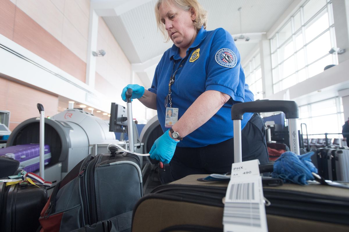 TSA officer Cindy Spencer sorts through luggage to be screened at a temporary check station on Thursday, March 30, 2017, at Spokane International Airport in Spokane, Wash. The airport is makeing changes to Concourse C., which has led to a redirection of checked baggage by passengers. For now, passengers will carry bags to this temporary check station that is used to screen for explosives. The temporary arrangement is making room for reconstruction on the back side of concourse where a new baggage check system is being installed. (Tyler Tjomsland / The Spokesman-Review)