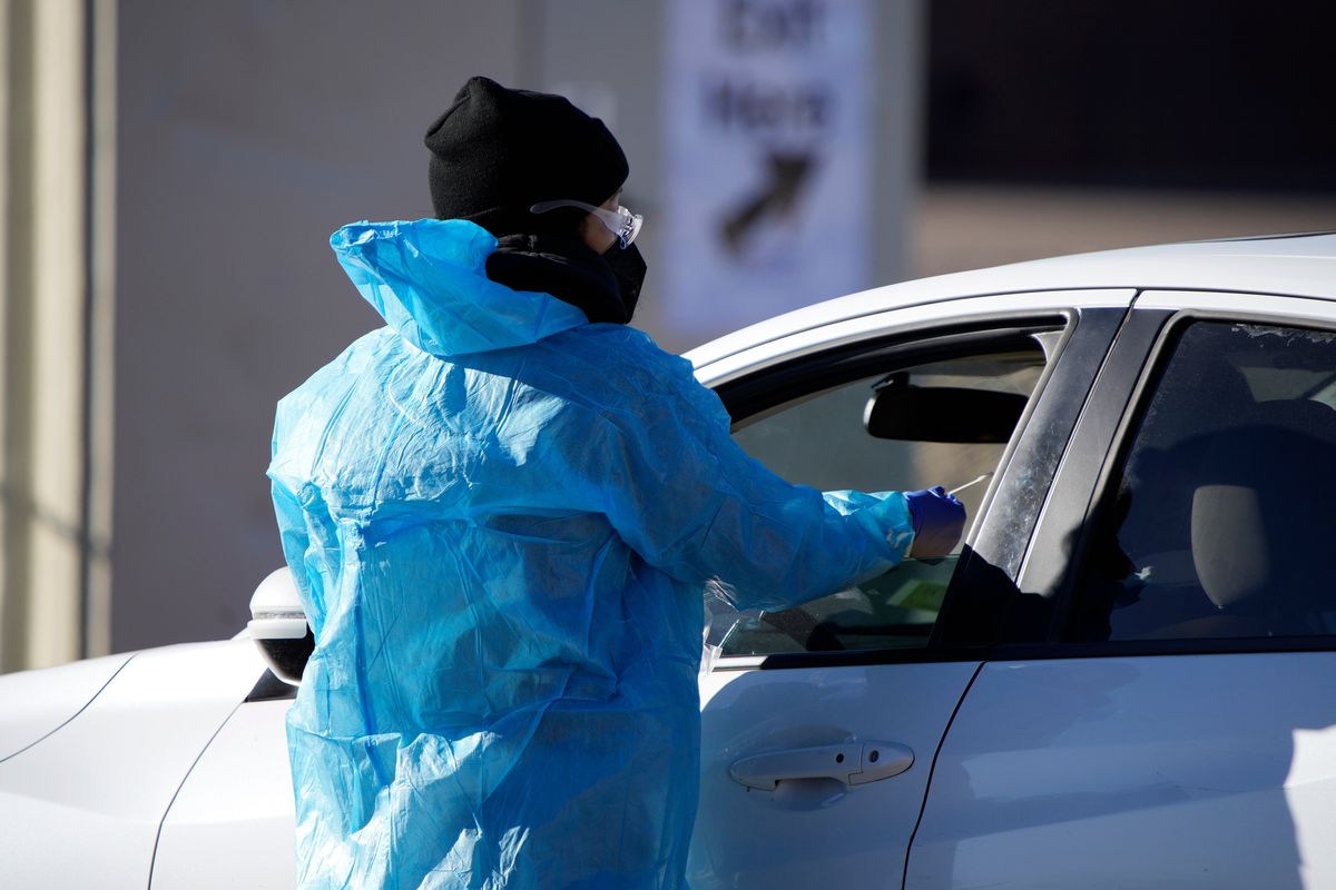 FILE - A medical technician performs a nasal swab test on a motorist queued up in a line at a COVID-19 testing site near All City Stadium Dec. 30, 2021, in southeast Denver.   (David Zalubowski)