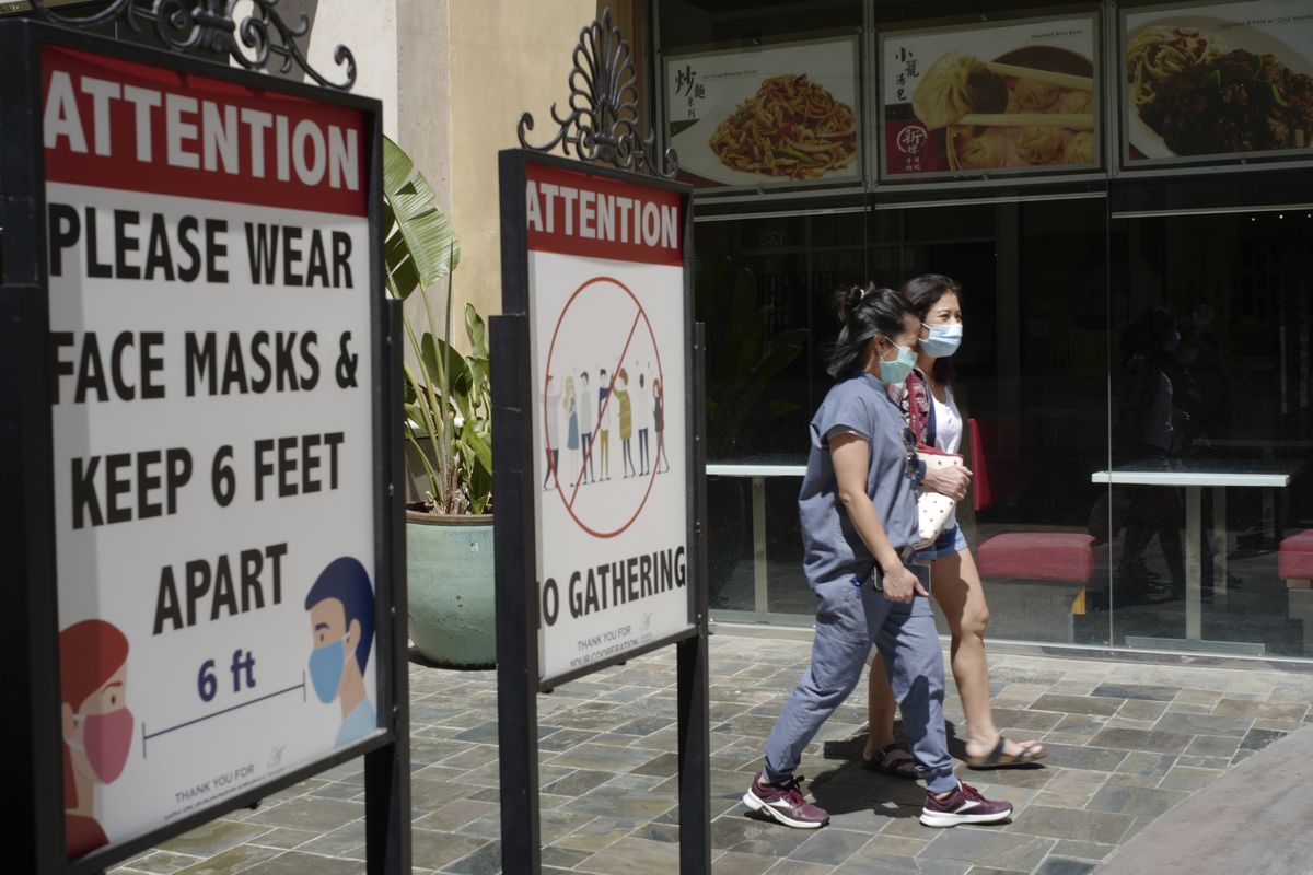 FILE - In this June 11, 2021, file photo, customers wear face masks in an outdoor mall with closed business amid the COVID-19 pandemic in Los Angeles. The latest alarming coronavirus variant, the delta variant, is exploiting low global vaccination rates and a rush to ease pandemic restrictions, adding new urgency to the drive to get more shots in arms and slow its supercharged spread.  (Damian Dovarganes)
