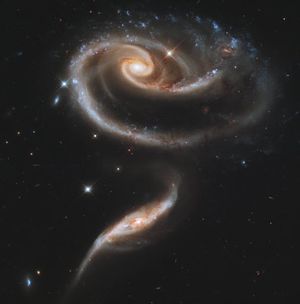 In this April 20, 2011 photo provided by NASA, the Hubble Space Telescope captures a group of interacting galaxies called Arp 273. The larger of the spiral galaxies, known as UGC 1810, has a disk that is tidally distorted into a rose-like shape by the gravitational tidal pull of the companion galaxy below it, known as UGC 1813. A swath of blue jewels across the top is the combined light from clusters of intensely bright and hot young blue stars. The smaller, nearly edge-on companion shows distinct signs of intense star formation at its nucleus, perhaps triggered by the encounter with the companion galaxy. A series of uncommon spiral patterns in the large galaxy is a tell-tale sign of interaction. Arp 273 lies in the constellation Andromeda and is roughly 300 million light-years away from Earth. Hubble was launched April 24, 1990, aboard Discovery's STS-31 mission.  (NASA / Associated Press)